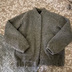 Grå teddyjacka från Vero Moda  - Mysig grå teddyjacka från Vero Moda i storlek XS. Jackan har en fluffig textur, raka ärmar och stängs med knappar framtill. Perfekt för kyliga dagar och enkel att matcha med olika outfits.🍂🐻🍪🧸