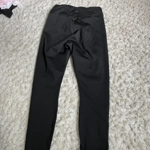 Svarta leggings från Adidas - Svarta tränings leggings .De har en tight passform och är tillverkade i ett stretchigt syntetmaterial som passar perfekt för träning eller chill. Klassisk design med hög midja och smala ben.