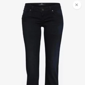 Svarta jeansbyxor från LTB - Snygga svarta jeansbyxor från LTB med klassisk femficksdesign och knappgylf. Modellen har en rak passform och låg midja, vilket ger en stilren och tidlös look. Perfekta att matcha med både sneakers och boots.