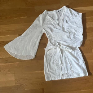 Vit omlottklänning från Trendyol - Säljer en fräsch vit kortklänning från Trendyol med omlott-design, v-ringning och vida långärmar. Klänningen har ett knytband i midjan och är gjord i ett lätt och luftigt linnematerial, perfekt för varma dagar. Ger Star Wars vibes, kan användas som kostym till Halloween exempelvis.