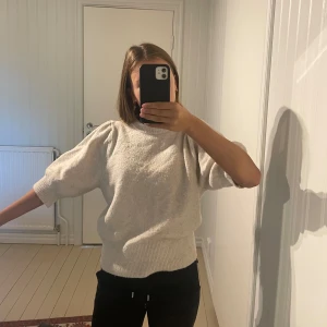 Ljusgrå stickad tröja från H&M - Supermjuk ljusgrå stickad tröja från H&M med bred ribbad mudd i nederkant och vid halsringning. Tröjan har halvkort ärm. Köpt 2023 så den säljs inte längre. Den har några noppror men de är inget man tänker på 💞💞
