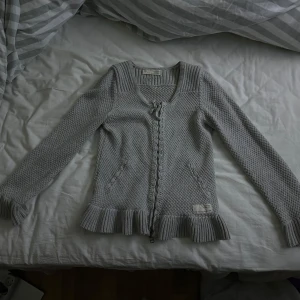 Grå kofta från Odd Molly med volang - Supersöt grå kofta från Odd Molly med stickad struktur, volangkant nertill. Koftan är i ny skick och knappt använd. Tröjan är i storlek 0 och pris kan diskuteras💗