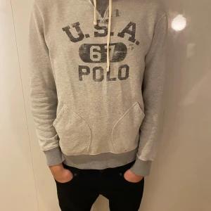 Grå hoodie från Polo Ralph Lauren - Snygg grå hoodie från Polo Ralph Lauren med tryck. Nytt pris ca 1900 mitt pris 499kr!