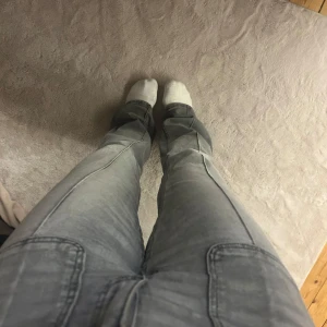 Grå jeansbyxor från Gina Tricot - Säljer ett par grå jeansbyxor från Gina Tricot i storlek 164. Byxorna har raka ben och klassisk femficksdesign med synliga sömmar längs benen. Perfekta för dig som gillar en enkel och stilren look.