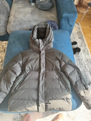 Svart pufferjacka från Parajumpers - Säljer en svart pufferjacka från Parajumpers Urban Puffers med huva och snyggt PJS-märke på ärmen. Jackan har dragkedjor vid fickorna och är fodrad med dun för extra värme. Perfekt för kalla dagar och har en clean, modern look.