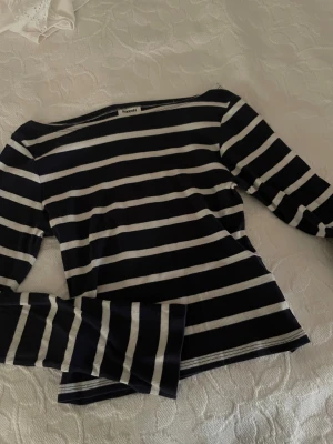 Randig långärmad tröja från Kappahl - Snygg långärmad tröja från Kappahl med marinblå och vita horisontella ränder. Tröjan har en klassisk, lite bredare halsringning och är gjord i mjuk bomull. Perfekt för dig som gillar enkel och stilren design med lite marint vibe.