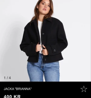 Svart kappa - Svart kappa från lager 157, modell: Brianna, i storlek XS. Jackan har en rak, loose passform, klassisk krage och stora fickor framtill. Stängs med knappar och har ett slätt, glansigt foder. Perfekt för dig som gillar stilrena och enkla plagg. 