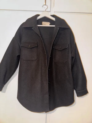 Svart kappa från NLY Trend - Svart oversize kappa från NLY Trend i storlek 38. Jackan har två stora bröstfickor med knapp. Långärmad och loose fit för chill vibe