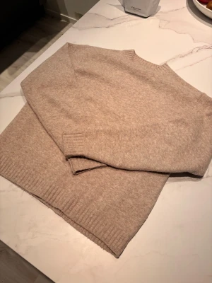 Beige stickad tröja från Uniqlo - !Rensar garderoben! Mysig beige stickad tröja från Uniqlo i storlek S. Tröjan har en enkel design med rund hals och ribbade muddar vid ärmslut och nederkant. Perfekt för att hålla sig varm under kyliga dagar och passar till allt. Jag är ca 180 cm lång och den passar mig perfekt!