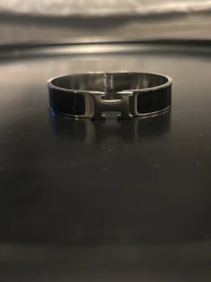 H- armband - Snyggt svart H- armband i metall. Den har en modern design som passar perfekt till din outfit. Metallens silvriga ton matchar den svarta emaljen för en lyxig känsla. Kom dm för mer bilder/frågor?!