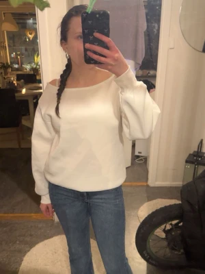 Vit offshoulder långärmad topp - Stilren vit topp med offshoulder-design och långa ärmar. Modellen är något loose och har en enkel, clean look som passar till jeans eller kjol. Materialet ser ut att vara bomull eller polyester för en mjuk känsla. Aldrig använt, fick den för någon dag sedan.