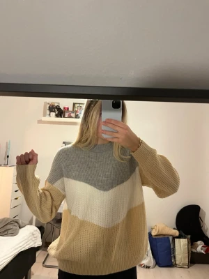 Beige grå och vit stickad tröja - Säljer en stickad tröja i beige, vitt och ljusgrått. Tröjan har breda ränder och rund hals. Materialet är mjukt och grovstickat. Väldigt bra skick, endast använd några gånger!!💛