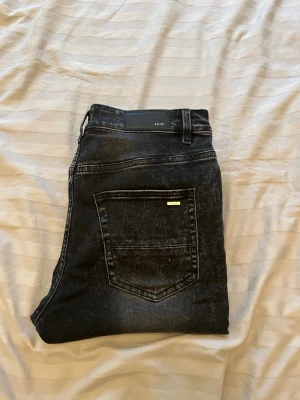 Svarta ripped jeans från Amiri - Snygga svarta jeans från Amiri med slitningar och tryck av en ängel på framsidan. Jeansen har smal passform, klassiska fickor och coolt streetwear-vibe. Perfekta för dig som gillar unik design och detaljer.