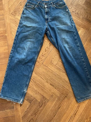 Blå raka jeans från Sweet Sktbs - Säljer ett par blå jeans från Sweet Sktbs med rak passform och broderad logga vid fickan. Jeansen har klassisk femficksdesign, slitna detaljer vid benslut och är tillverkade i denim. Perfekta för en avslappnad streetstil.