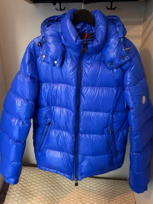 Moncler Maya – Blå (Storlek 3) - Säljer en äkta Moncler Maya i blå färg. Jackan är mycket sparsamt använd, i mycket gott skick (9/10) och utan synliga tecken på användning. Alltid väl omhändertagen.  Färgen säljs inte längre, vilket gör jackan mer ovanlig och eftertraktad. Klassisk modell med hög kvalitet och värme.  Info: 	•	Modell: Moncler Maya 	•	Färg: Blå (utgången) 	•	Storlek: 3 	•	Skick: 9/10  Äkthet: 	•	100 % äkta 	•	Kvitto finns ej kvar 	•	Äkthet kan kontrolleras via QR/Certilogo 	•	Fler bilder kan skickas vid önskemål