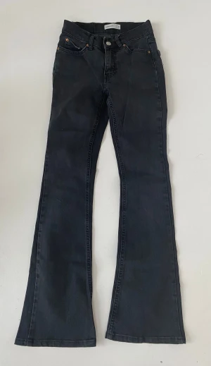Svarta lågmidjade  bootcut jeans från Gina Tricot - Snygga svarta bootcut jeans från Gina Tricot med klassisk femficksdesign och utsvängda ben. Jeansen har lågmidja och är tillverkade i denimtyg. Perfekta för en trendig och avslappnad stil.