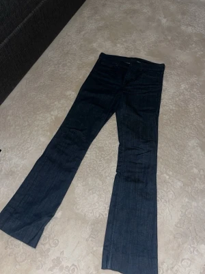 Mörkblå bootcut jeans - Snygga mörkblå bootcut jeans med klassisk femficksdesign och normalhög midja. Jeansen har en rak passform över låren och lätt utsvängda ben. Perfekta för dig som gillar en tidlös och stilren look.