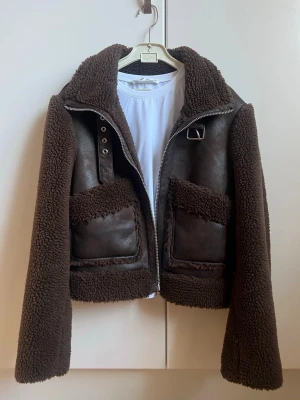 Mörkbrun teddyjacka med detaljer - Säljer en mörkbrun teddyjacka med stora fickor. Jackan har mjukt, fluffigt teddy-material på insidan. Aldrig en gång, är som ny. Säljer då jag har för mycket jackor. slutsåld från bershka. Nypris 700. XS men passar även S. 