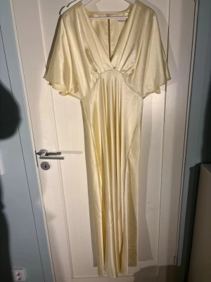 Lång champagnefärgad satinklänning - Superfin klänning i satin! Använd en gång, MEN på bilderna finns det lite småfel som är lite överallt på klänningen (inte tydligt men om man kollar noga) tidigare pris då jag köpte den var för 1 500kr. 