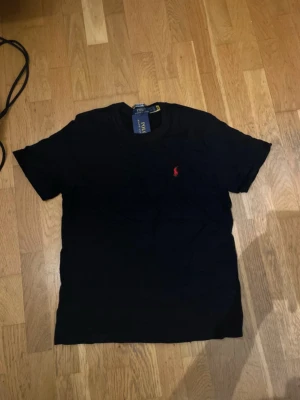 Svart t-shirt från Ralph Lauren - Klassisk svart t-shirt från Ralph Lauren med rött märke, tröjan är väldigt Grisch och priset går att diskutera 