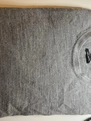 Grå merinoulltröja Galeries Lafayette - Snygg grå stickad tröja från Galeries Lafayette i 100% merinoull. Klassisk rund halsringning och enkel design som passar perfekt till det mesta. Supermjuk och tunn, perfekt för lager-på-lager-stil eller bara en classic look.