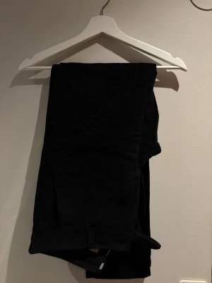 Svarta manchesterbyxor herr - Säljer ett par svarta manchesterbyxor med klassisk rak passform och diskreta fickor. Byxorna har tydlig manchesterstruktur och bälteshällor i midjan. Perfekta för dig som vill ha en stilren och tidlös look.