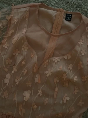 Ljusrosa blommig klänning från SHEIN - Superfin ljusrosa klänning från SHEIN med transparent överdel och 3D-blommor. Klänningen har rund hals, dragkedja i ryggen och är gjord i ett lätt, syntetiskt material. Den har långa, transparenta ärmar och ett romantiskt blommigt mönster över hela överdelen. Kan diskutera pris!