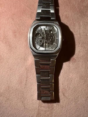 Ingen väst på bilderna - Bilderna visar en automatisk ”OCTAGON AUTOMATIC F10050”armbandsklocka i silverfärgat metall med genomskinlig urtavla och länkarmband. Nypris 3 595kr