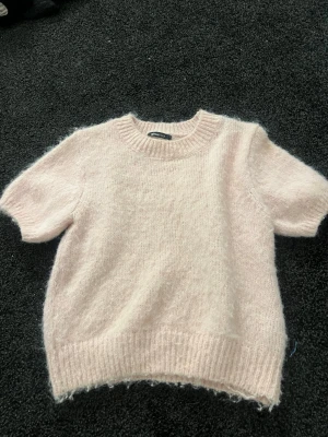 Ljusrosa stickad tröja Gina Tricot - Supermjuk ljusrosa stickad tröja från Gina Tricot med korta ärmar och ribbade muddar. Perfekt för lager på lager och ger en söt vibe till din outfit. Passar dig som gillar en enkel men mysig look.