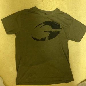 Olivgrön t-shirt från GASP med tryck - Olivgrön t-shirt från GASP i bomull med stort svart logotryck på bröstet. Klassisk rund hals och korta ärmar. Perfekt för dig som gillar en enkel men sportig stil.