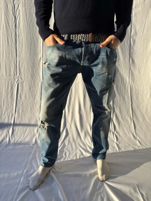 Dondup George  - Säljer ett par blå jeans med lite schystare slitningar och hål på båda benen. Använt fåtal gånger. Är storlek 38 men passar allt från 34. Vid frågor eller funderingar är det bara att höra av er.