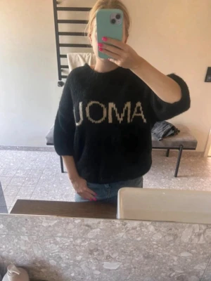Svart stickad tröja från Noella - Cool svart stickad tröja från Noella med vit text 'AMOUR' framtill. Tröjan har en loose passform och trekvartsärmar, perfekt att slänga på sig till jeans. Mjuk och fluffig känsla, passar dig som gillar avslappnad stil.