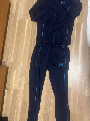 Inga skor på bilderna - Bilderna visar ett träningsset från Under Armour med tröja och byxor, men inga skor finns med.