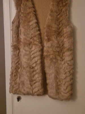 Mysig väst - Beige väst med fejkpäls på framsidan och stickad baksida. Storlek L. Från Stradvarius. Nyskick! 