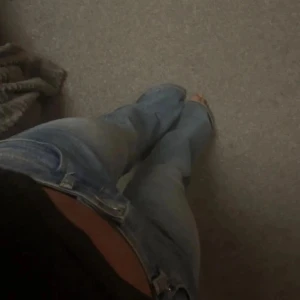 Ljusblå bootcut jeans med låg midja - Säljer ett par klassiska blå bootcut jeans från H&M Divided i storlek 36. Jeansen har låg midja, fem fickor och snyggt utsvängda ben. Dom har ett jättelitet hål på ena fickan där bak med det syns knapt