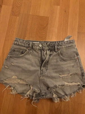 Gråa jeansshorts Zara - Säljer ett par gråa jeansshorts från Zara i storlek 36. De har slitna detaljer, fransiga kanter och klassisk femficksdesign. 