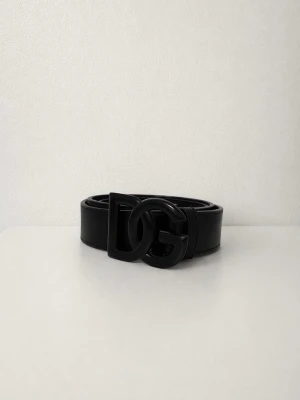 Svart DG bälte i skinn - Säljer ett svart DG skärp från Dolce & Gabbana med bred design och stor DG-logga i metall framtill. Skärpet är gjort i äkta skinn och har en stilren look som passar till jeans eller kostymbyxor. Perfekt accessoar för att lyfta din outfit. Har aldrig använts och har bara legat i mitt garderob. Vill bara bli av med den