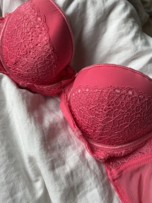 Rosa spetsdetaljerad bh💗70c - Snygg rosa bh med vadderade kupor och spetsdetaljer framtill💕storlek 70c 🩷har en liten rosett i mitten och har justerbara axelband💗nästan aldrig använd, har bara legat i garderoben 💓