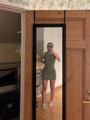 Olivgrön ribbad kortklänning - Säljer en tight, olivgrön ribbad klänning med ärmlös design och rund hals. Klänningen är kort och sitter figurnära, perfekt för dig som gillar en enkel men snygg stil. Materialet är stretchigt och bekvämt. Fråga mig om ni undrar något 😊