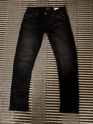 Replay svarta jeans, straight fit - Svarta jeans från Replay med klassisk femficksdesign och snygga detaljer på bakfickorna. Jeansen har en straight fit-passform. Perfekt för dig som gillar en stilren look med lite edge.