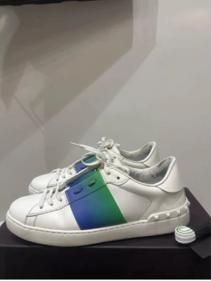Valentinos open  - Säljer ett par Valentino Rockstud sneakers i vitt skinn med cool blå och grön färgpanel på sidan. Allt og medföljer först till kvarn skick 8.5/10 storlek 41-42