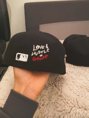 Svart New Era White Sox keps 59FIFTY - Säljer en svart New Era 59FIFTY keps från Cooperstown Collection med White Sox brodyr framtill och coolt hjärtdetalj med baseboll. Kepsen har broderade texter och World Series 05 patch på sidan. Materialet är 100% polyester.