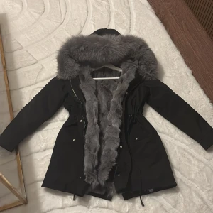 Luxeswe parkajacka - Parkajacka i svart med lyxig 🦊 päls på insidan och runt huvan. Jackan har dragsko i midjan, dragkedja och knappar framtill. Pälsen är supermjuk och ger en riktigt exklusiv vibe.  Varmaste jackan som finns verkligen!! Från Luxeswe.com nypris är 3499:-
