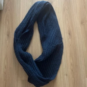 Mörkblå tubhalsduk  - Säljer en mörkblå tubhalsduk. Halsduken är grovstickad och har en enkel, stilren design som passar perfekt när det är kallt ute. Materialet är 100% polyakryl vilket gör den mjuk och skön att ha på sig. Perfekt att slänga på sig för extra värme.