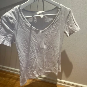 Vit v-ringad topp från H&M - En enkel och stilren vit topp från H&M med v-ringning och korta ärmar. Tillverkad i mjuk bomull som känns skön mot huden. Perfekt att matcha med jeans eller kjol för en clean look.
