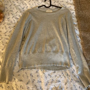 Grå stickad tröja med guldfärgade knappar - Supersnygg ljusgrå stickad tröja från Lindex med guldfärgade knappar både bak i nacken och vid ärmsluten.  Väldigt fint skick🩷🙏🏼