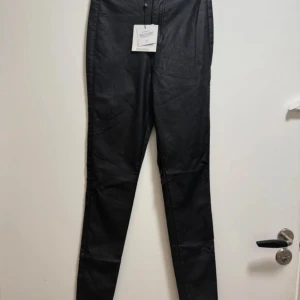 Vice High Waist Skinny Jeans Svart - Svarta high waist skinny jeans från Vice med coated finish som ger en snygg glansig look. Modellen är tight och har klassisk femficksdesign. Perfekta för dig som gillar en stilren och edgy vibe.