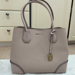 Michael Kors i Soft pink  - Stilren handväska i mjukt rosa skinn från Michael Kors, Mercer Corner-modell. Väskan har guldfärgade detaljer, dubbla handtag, avtagbar axelrem och mittfack med dragkedja. Aldrig använt, med tagg. Pris kan diskuteras.