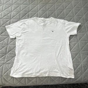 Vit t-shirt från GANT i bomull - Vit t-shirt från GANT med liten logga på bröstet. Klassisk rund halsringning och korta ärmar. Tillverkad i mjuk bomull för en skön känsla. Perfekt basic-plagg att ha i garderoben.