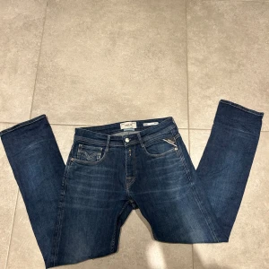 Replay Rocco jeans - Snygga blå jeans från Replay, modell Rocco. Klassisk femficksdesign med kontrastsömmar och Replay-logga på bakfickan. Jeansen har rak passform och är tillverkade i slitstarkt denim med en cool tvättad look. Perfekt för dig som gillar stilrena och tidlösa jeans.